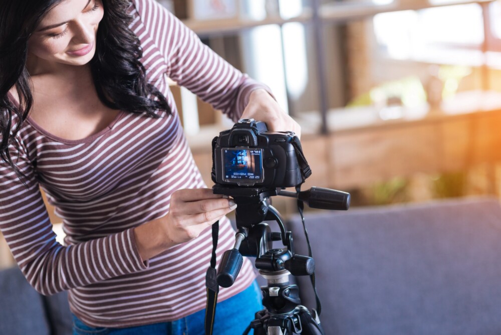 Delighted person holding a camera and putting it on a tripod