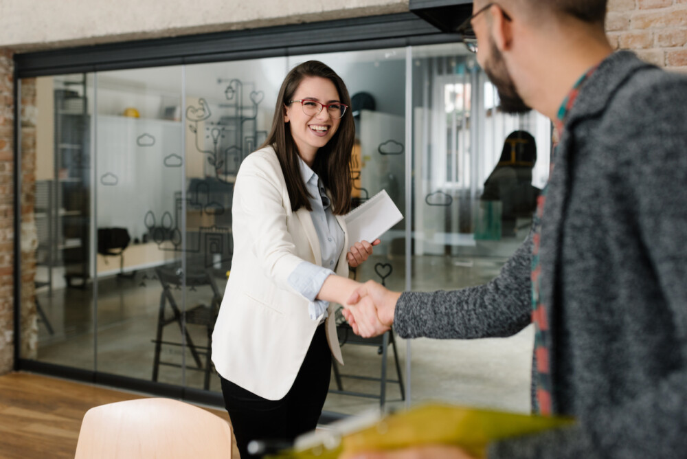 woman smiling while shaking hands in job interview