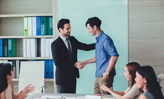 Two people shaking hands in an office setting.