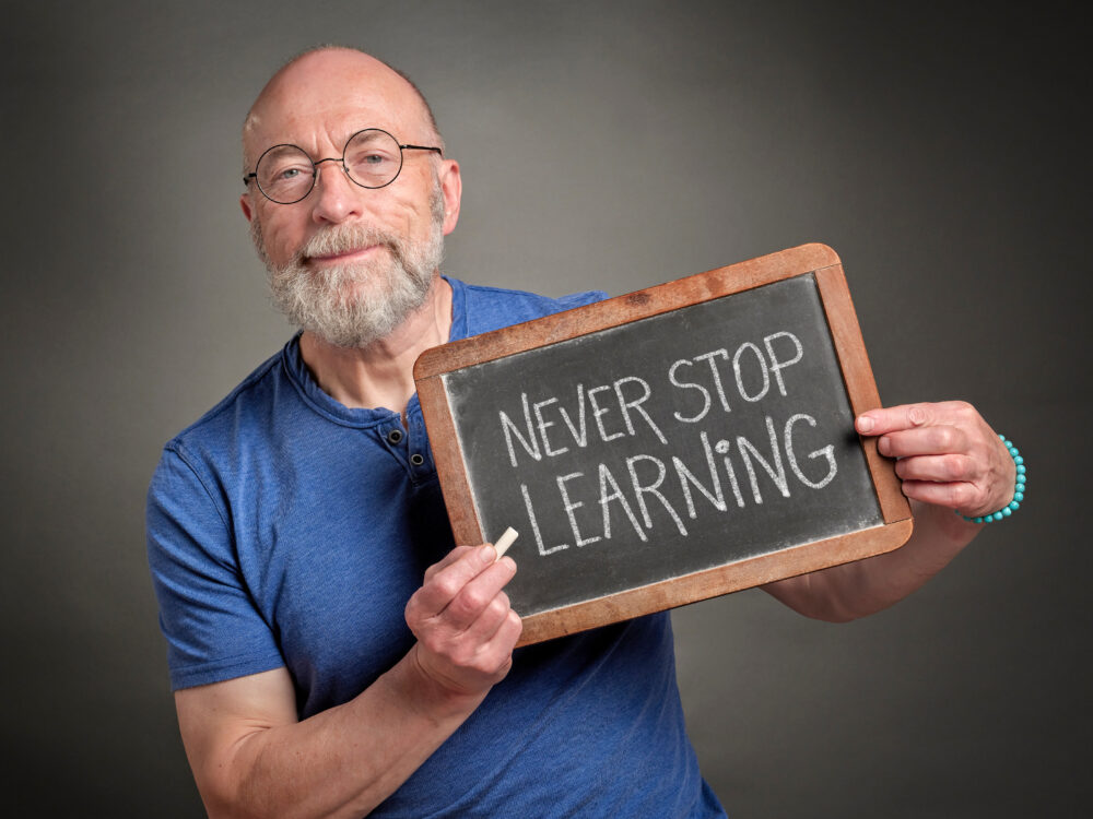 Man holding never stop learning chalk sign