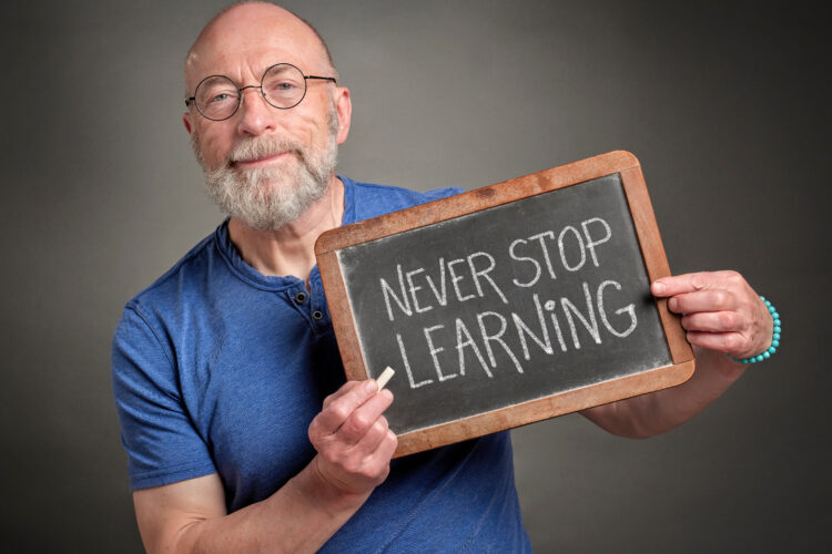 Man holding never stop learning chalk sign