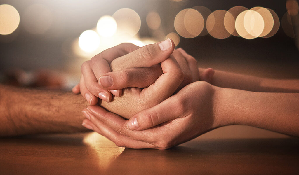 Cropped shot of a couple holding hands against a night time background