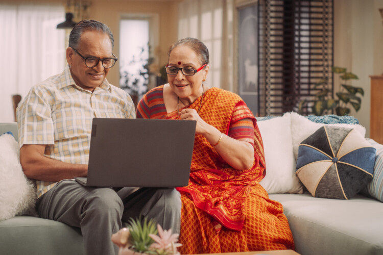 elderly couple looking at computer on couch