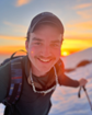 Lukas Kopacki smiling in an alpine setting with the sun in the background