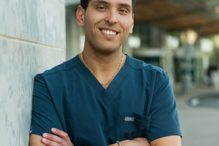 A smiling Post-Baccalaureate Pre-Medical student outside of a hospital