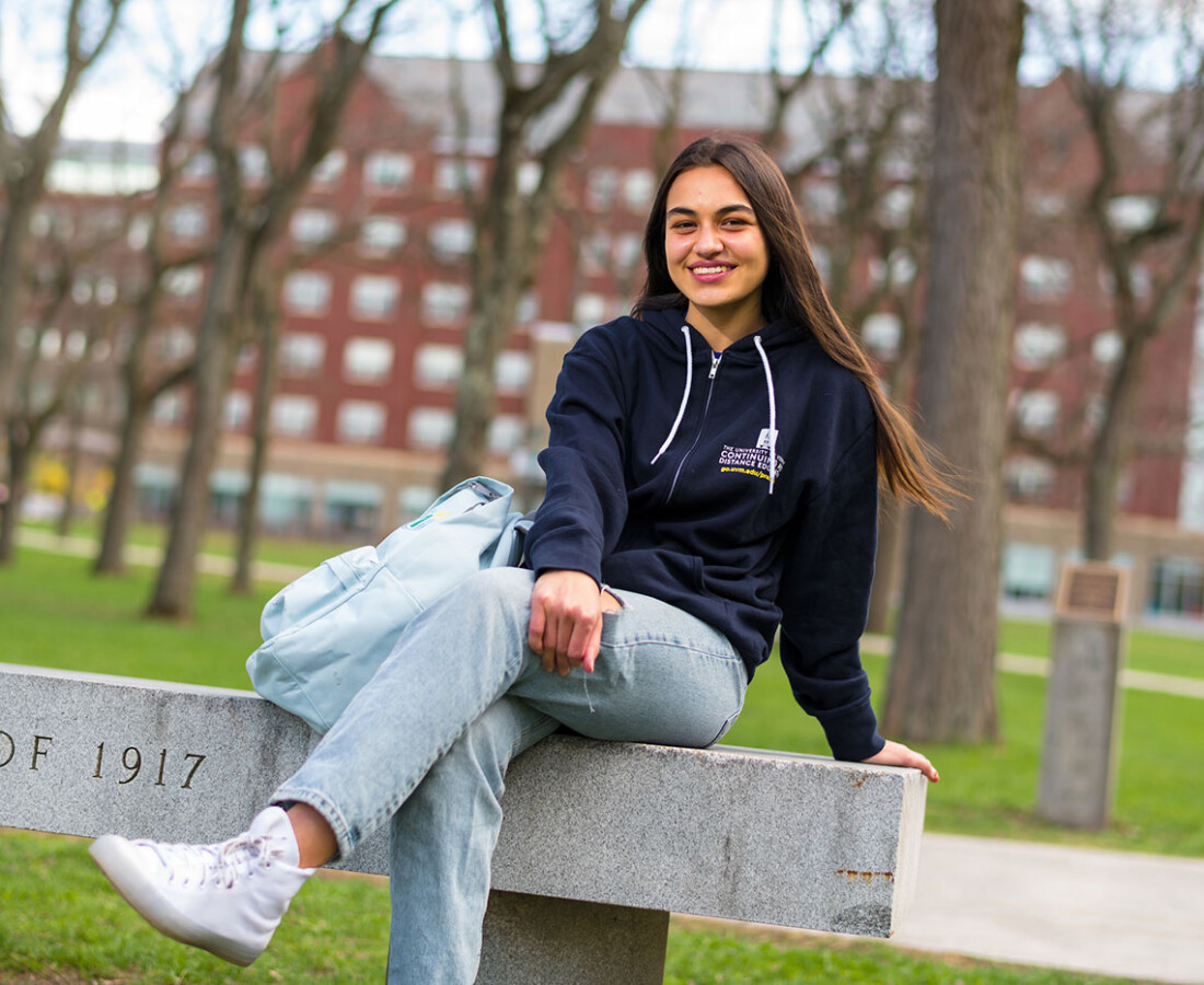 Izzy sitting on a bench on the UVM campus