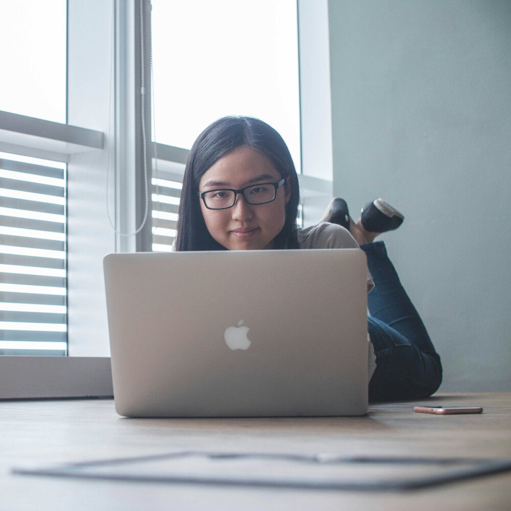 Student laying on the floor using a laptop