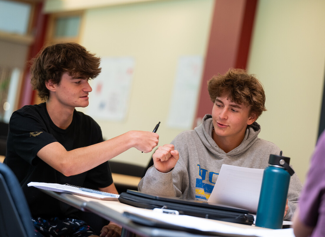 Summer Academy students fist bumping sitting at a desk