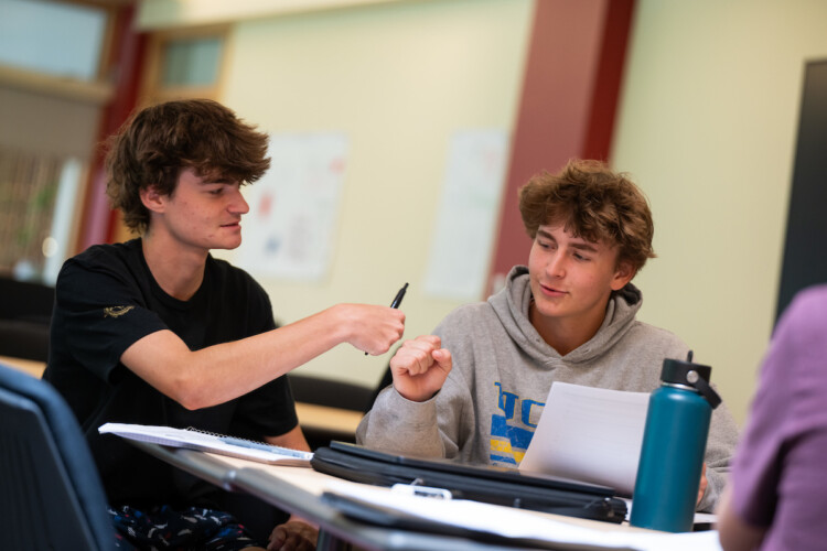 Summer Academy students fist bumping sitting at a desk