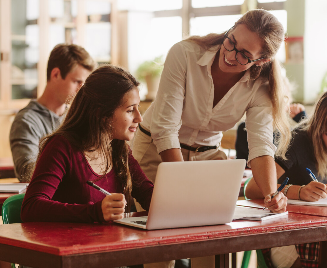 Smiling female teacher helping student during her class.