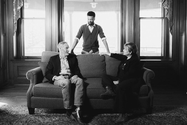 three faculty members have a conversation in a library