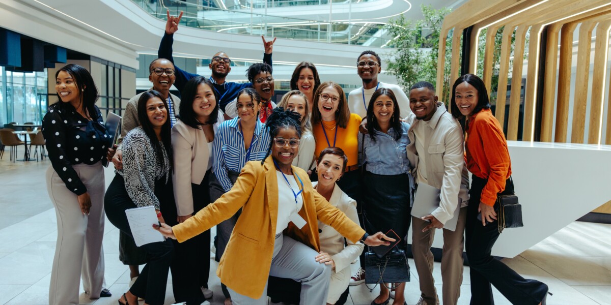 Leadership and team gathered in a group photo, all smiling at camera with office in the background.