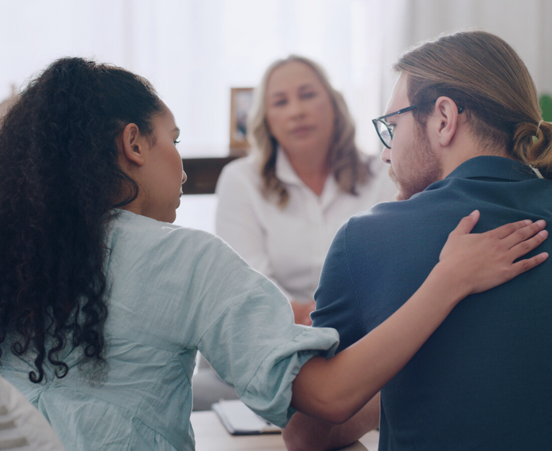 A woman and a man in a therapist's office receiving support and guidance from a psychologist or social worker during a counseling session.