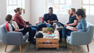Group of adults sitting around a coffee table in discussion.