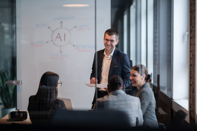 Businessman in a dark suit presenting to colleagues in a glass-walled meeting room, with an AI diagram on the whiteboard.