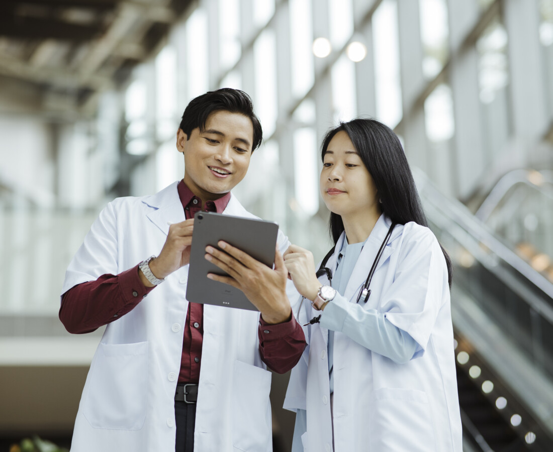 Healthcare Professionals Reviewing Information on Tablet in Hospital Entrance.